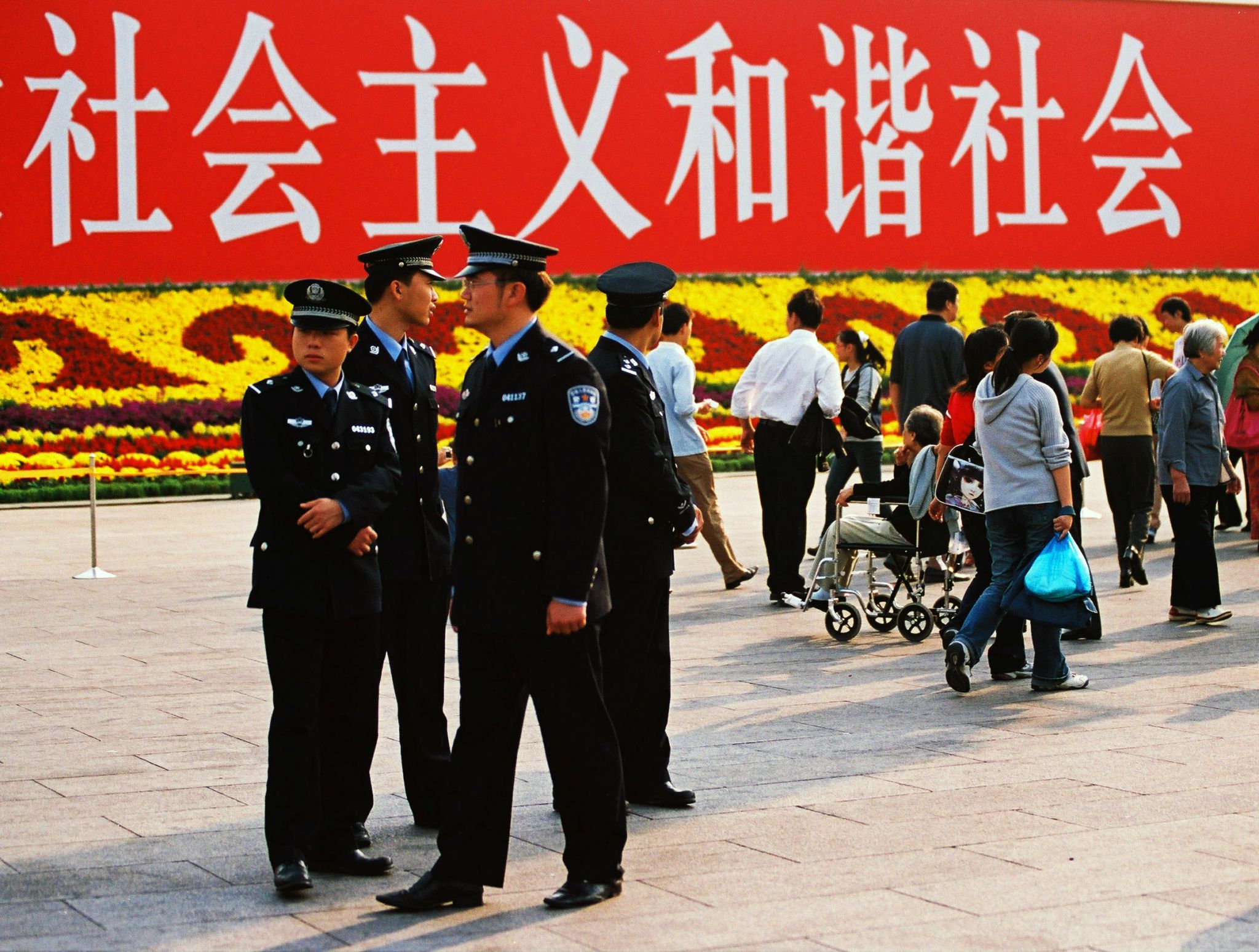 Policja patrolująca Plac Tiananmen. październik 2005 r. napis w tle mówi: "Socjalizm, harmonijne społeczeństwo".