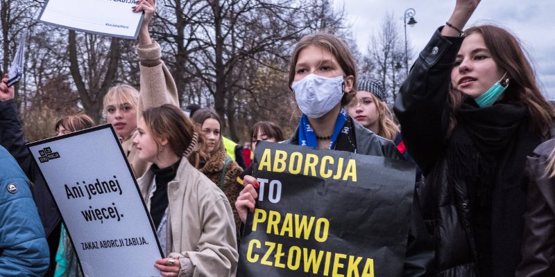 Grupa młodych kobiet trzymających transparenty proaborcyjne na manifestacji ulicznej.