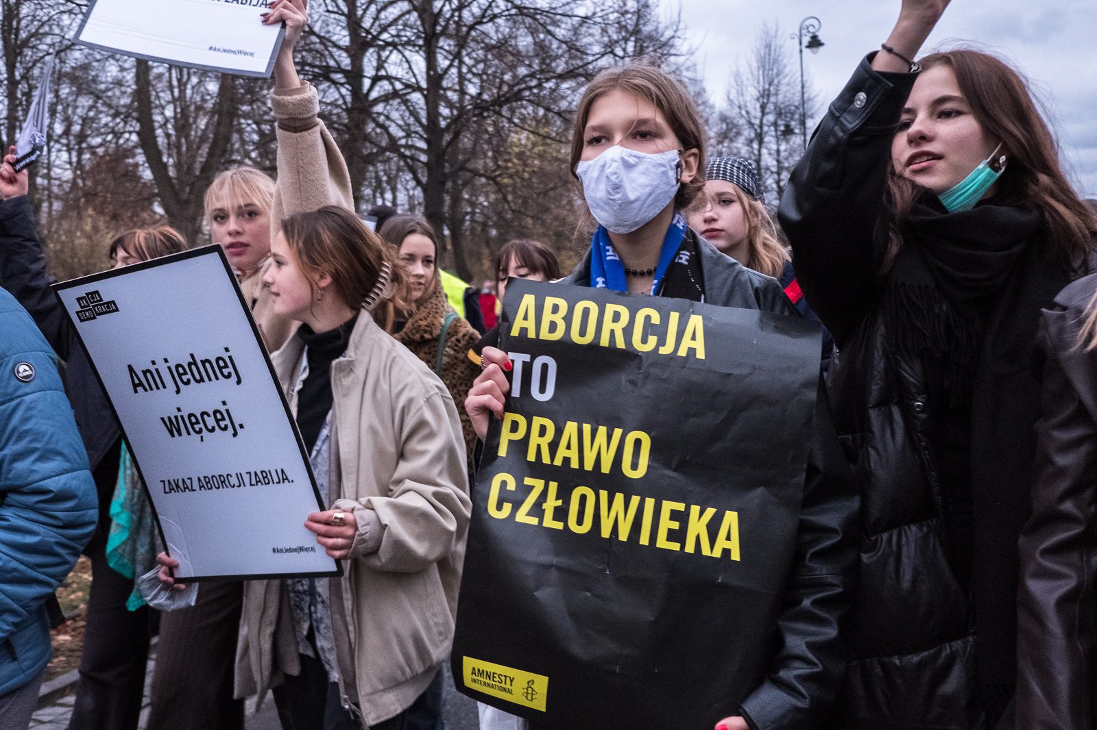 Zdjęcie z demonstracji strajku kobiet pod hasłem "Ani jednej więcej. Grupa młodych kobiet, jedna z nich trzyma baner z logiem Amnesty International i hasłem: Aborcja to prawo człowieka". Warszawa, 6 listopada 2022.