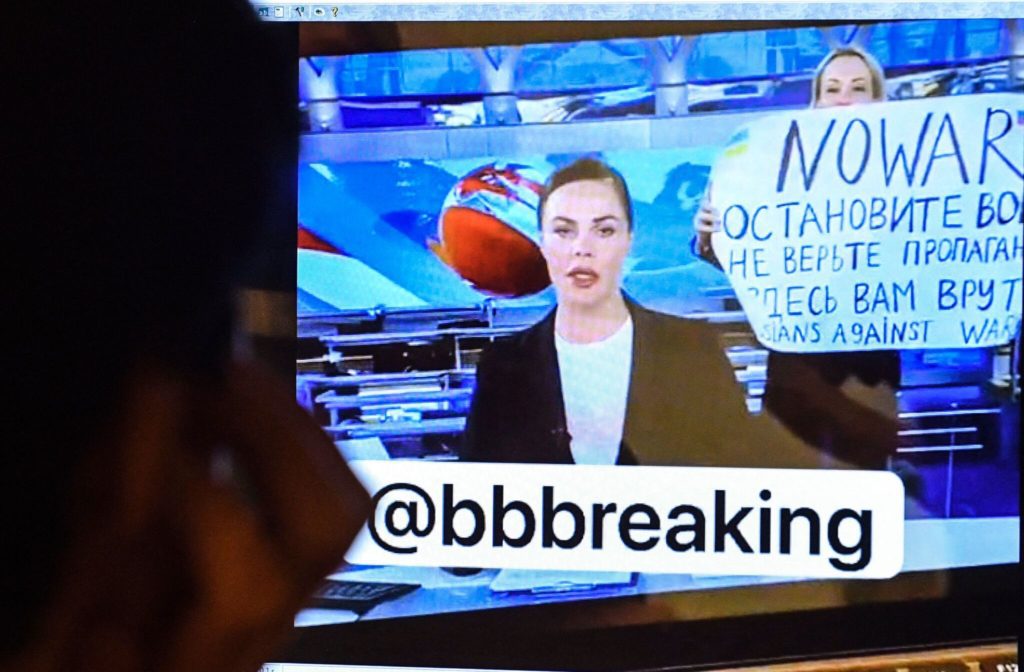 Mężczyzna patrzy na ekran komputera, oglądając jak pracowniczka rosyjskiego programu pierwszego, Maria Owsiannikowa, wchodzi do studia telewizyjnego Ostankino podczas najchętniej oglądanego wieczornego programu informacyjnego w Rosji, trzymając plakat z napisem „Nie wojnie” i potępiający działania militarne Moskwy w Ukrainie, Moskwa 14 marca 2022 r.