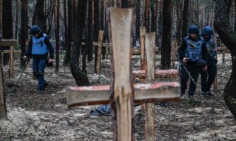 Ukraińscy żołnierze szukają min lądowych na miejscu pochówku w lesie na obrzeżach Izium, wschodnia Ukraina, 16 września 2022 r.
