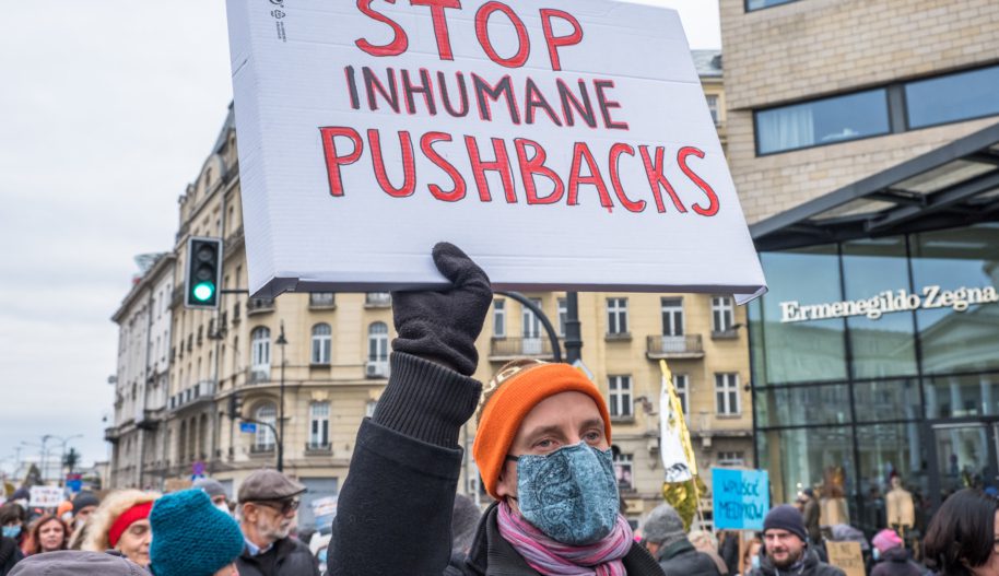 Osoba trzymająca transparent wzywający do zaprzestania pushbacków na granicy.