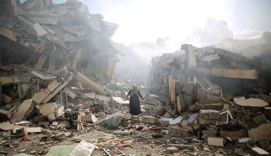 Kobieta stojąca pośród ruin budynków po bombardowaniu.