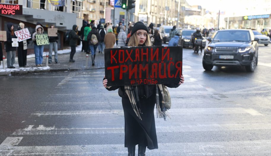 Młoda kobieta trzyma transparent na demonstracji w Kijowie.